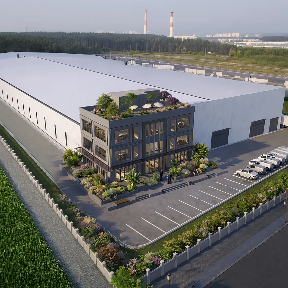 Fabrika yerleşkesinin havadan görünümü: uzun üretim holünün önüne yerleşen üç katlı koyu renkli yönetim binası, çatısında yeşil teras; önde otopark ve peyzaj bantları